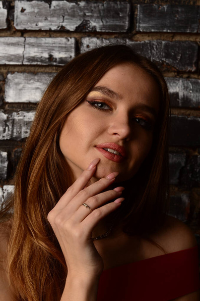 A beautiful young girl in a red dress in the studio. Luxury jewelry, necklaces, and rings, bright makeup, red lips, manicure. Glamorous luxury lady. - Zdjęcie, obraz