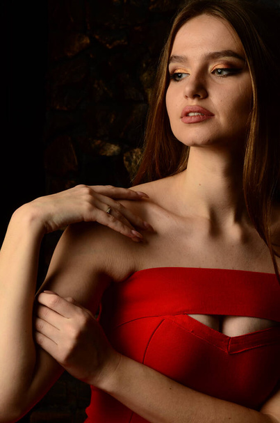Kaunis nuori tyttö punaisessa mekossa studiossa. Ylellisiä koruja, kaulakoruja ja sormuksia, kirkasta meikkiä, punaiset huulet, manikyyri. Lumoava luksusnainen.. - Valokuva, kuva
