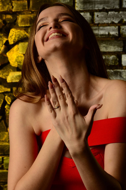 Una hermosa joven con un vestido rojo en el estudio. Joyas de lujo, collares y anillos, maquillaje brillante, labios rojos, manicura. Glamorosa dama de lujo. - Foto, Imagen