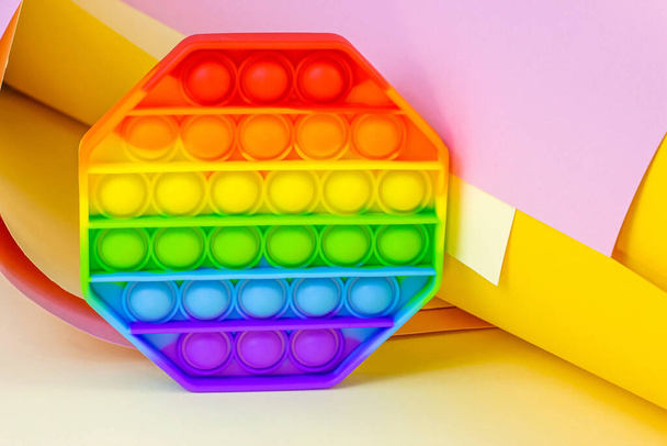 Trendy einfache Grübchen oder pop it sensorisches Spielzeug für Kinder auf hellem Papier Hintergrund. Beliebte Antistress-Silikon-Kinder zappeln in Regenbogenfarben. - Foto, Bild