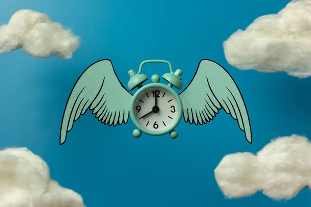 Flying blue alarm clock with wings under the clouds. Levitation concept. Time to change. Eight hours. Copy space. - Photo, Image