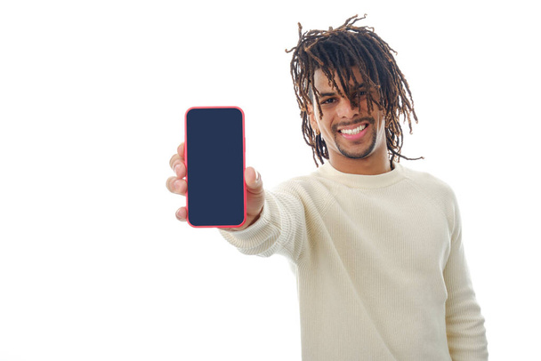 Lateinischer Mann zeigt Mobiltelefon mit leerem Bildschirm vor Kamera, während er auf isoliertem Hintergrund steht. - Foto, Bild