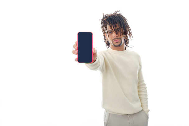 Serious man showing blank screen mobile phone to camera while standing on isolated background. - Foto, immagini