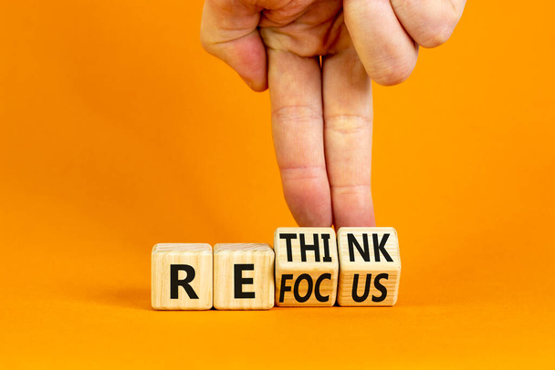 Refocus and rethink symbol. Businessman turns cubes and changes the word 'refocus' to 'rethink'. Beautiful orange table, orange background. Business refocus and rethink concept. Copy space. - Fotografie, Obrázek