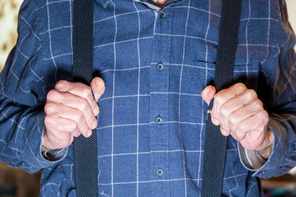 Um homem de camisa azul segura as mãos em suspensórios - Foto, Imagem
