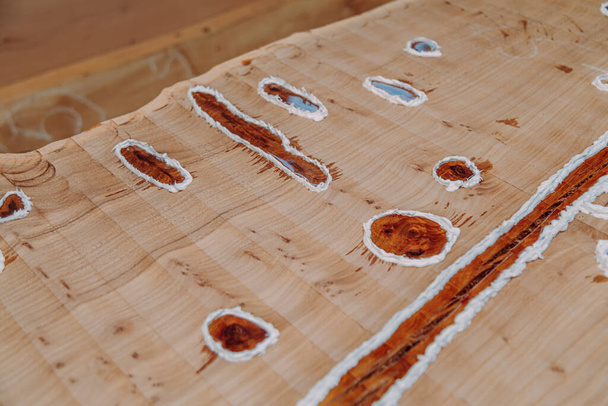 Close-up van gedroogde epoxyhars in houten tafel. Proces van het maken van een ambachtelijke hars en houten tafel - Foto, afbeelding
