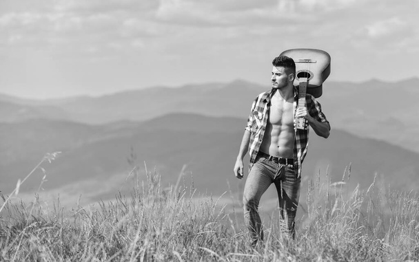 Hits you love. happy and free. cowboy man with bare muscular torso. acoustic guitar player. country music song. sexy man with guitar in checkered shirt. hipster fashion. western camping and hiking - 写真・画像