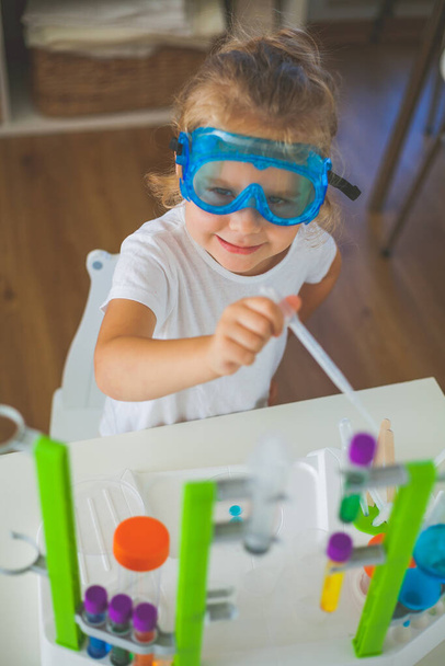 Nauka. Little cute girl ustawia eksperymenty w domu, kolorowe płyny, laboratorium instalacji dziecka. Szkoła. - Zdjęcie, obraz