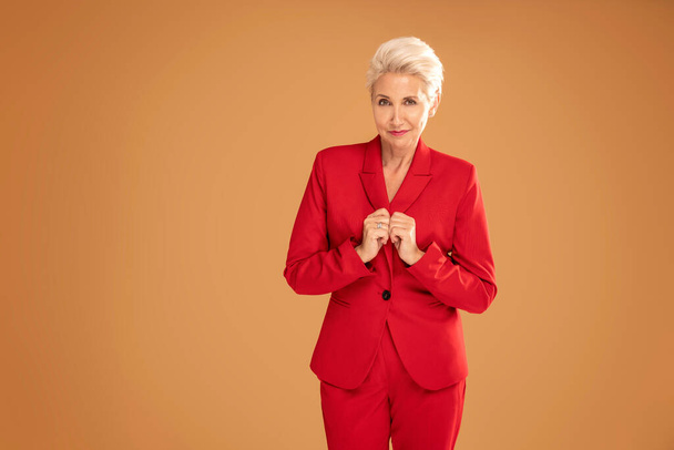 Fashion photo of elegant business woman in a red suit isolated at the studio background. Beautiful attractive blonde caucasian lady looking at the camera. - Fotó, kép