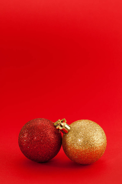 два блестящих рождественских шара красного и золотого цветов на красном фоне - Фото, изображение