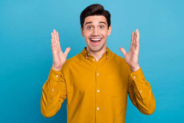 Photo of excited surprised crazy guy open mouth raise palms wear yellow shirt isolated blue color background - Foto, Imagen