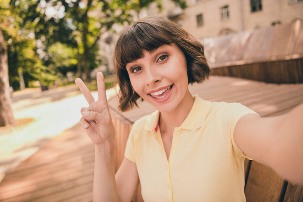 Photo of funny young brunette lady do selfie show v-sign wear polo outside in city - Zdjęcie, obraz