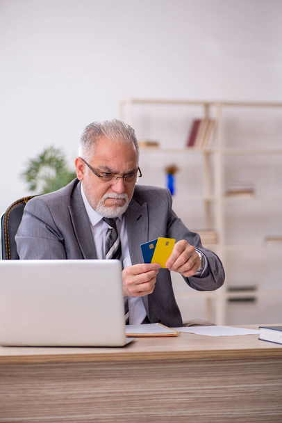 Starý muž zaměstnanec držící kreditní kartu v kanceláři - Fotografie, Obrázek
