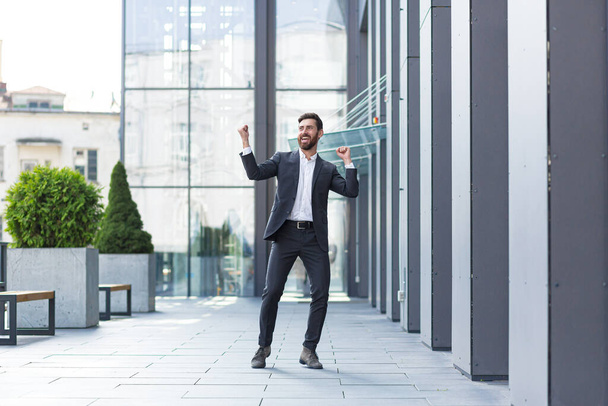 Cheerful happy business man dancing walk the city street background a modern office building outside, outdoors Funny successful businessman in suit celebtes victory - Foto, immagini