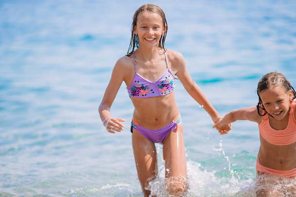 Чарівні маленькі дівчата розважаються на пляжі
 - Фото, зображення