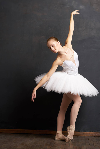 femme ballerine dans un blanc tutu danse posant performance sombre fond - Photo, image