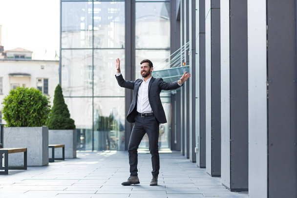 Successful male freelancer in a business suit dances near the office celebrates a winning deal, and a good end to the working day - Photo, Image