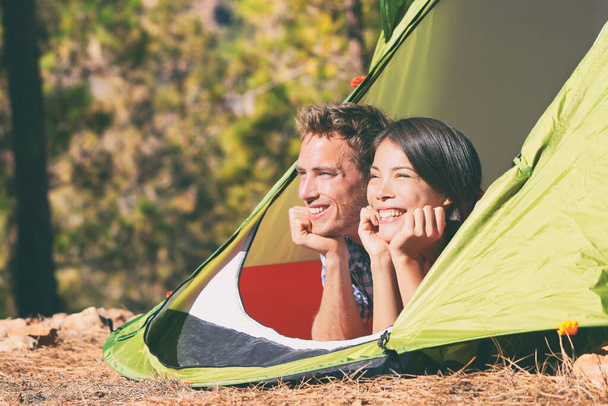 Dois jovens relaxando na barraca de acampamento no verão ao ar livre natureza montanhas floresta. Casal feliz turistas relaxando ao sol, férias de viagem. Acampantes lá fora. - Foto, Imagem