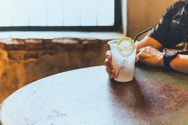 Homem mão segurando vidro de água fria espumante com fatias de limão. - Foto, Imagem