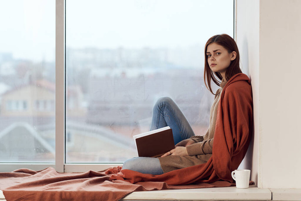 woman with a book near the window with a cup of coffee - Foto, Bild