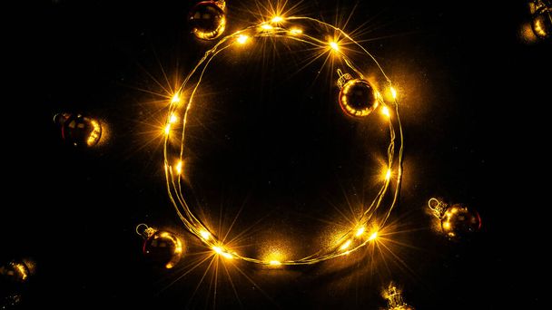 Kerstlichtgrens. Gouden licht slinger decoratie, gouden bol geïsoleerd op zwart voor Kerstmis partij ornament decor achtergrond. Gloeilampen voor kerstvakantie - Foto, afbeelding