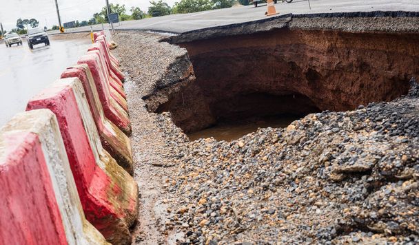 The road was destroyed by water erosion caused by heavy rain and flooding the road. - Photo, Image
