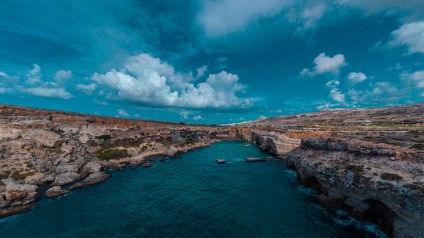 Aerial drone Panorama of picturesque bay in Malta called Popeye village, former movie set and now a beautiful beach with houses and cliffs emerging from water. - Fotografie, Obrázek