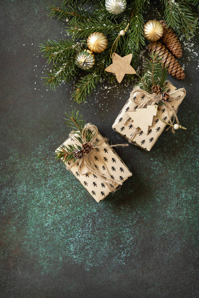 Holiday concept. Christmas or New Year layout with fir tree branch and Christmas present on a dark green stone background. Flat lay, copy space. - Fotografie, Obrázek
