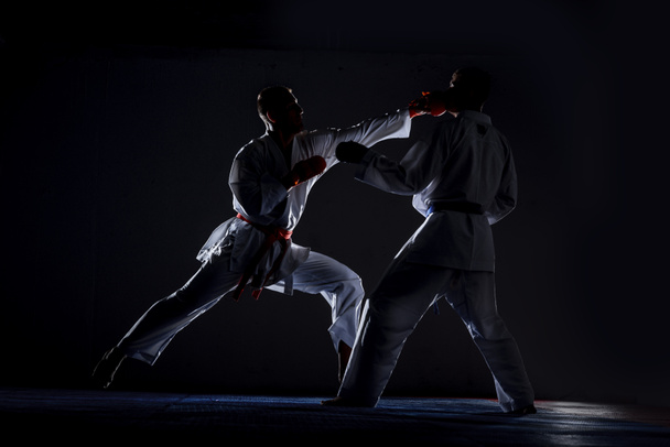 Silný fit sportovec, karate muž nebo bojovník v bílém kimonu, oblek, s opaskem pózuje v bojovém postoji - Fotografie, Obrázek