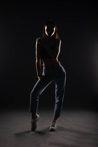 Silhouette eines jungen und schönen Mädchens, das seine Haltung hält, während es im Studio posiert - Foto, Bild