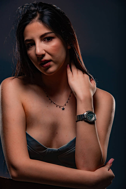 Attractive and beautiful girl is posing in stuido on dark background while touching her neck - Photo, Image
