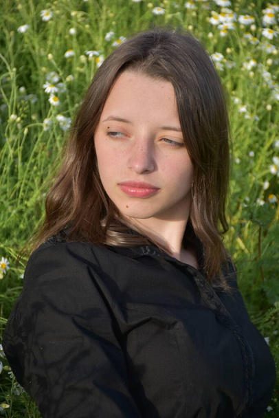 a girl in a black dress sits in the grass, - Φωτογραφία, εικόνα