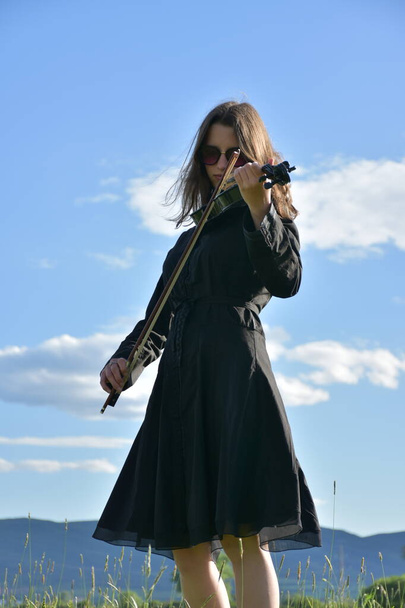 une fille dans une robe noire avec un violon noir, - Photo, image