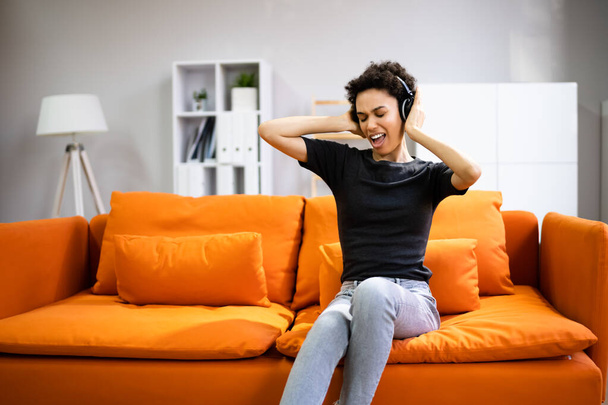 African American Woman Enjoying Music Through Headphones In At Home - Фото, изображение