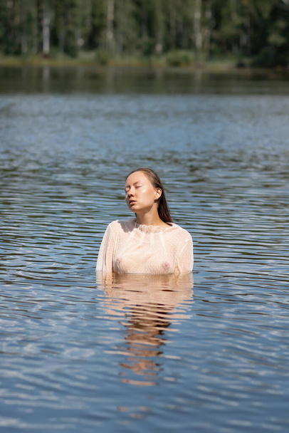 Tarjous viettelevä nainen valkoinen märkä läpinäkyvä paita seisoo vedessä lampi ja katselee pois - Valokuva, kuva