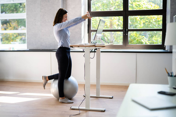 Worker Stretch Exercise At Stand Desk In Office - Foto, Bild