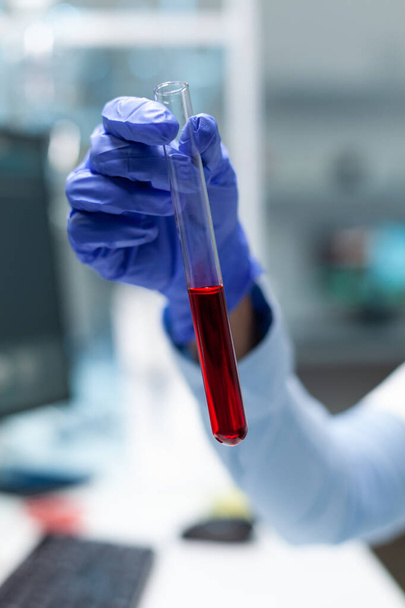 Primer plano del biólogo químico que sostiene el tubo de ensayo médico con el tratamiento del virus en desarrollo de sangre - Foto, imagen