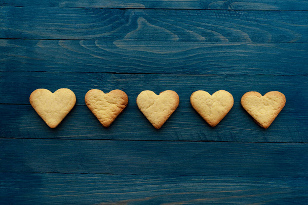 Row of five heart cookies on wooden blue background horizontal photo - 写真・画像
