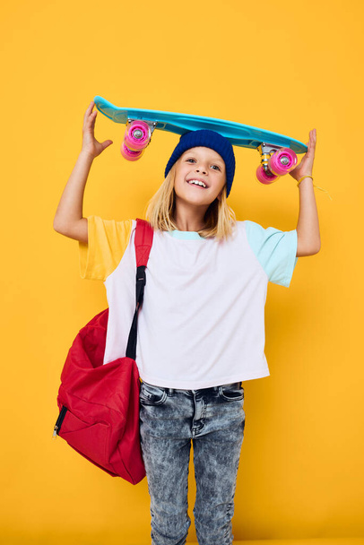 tiener met een skateboard op gele achtergrond. Hoge kwaliteit foto - Foto, afbeelding