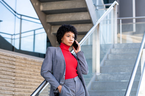 A young African-American businesswoman talking on the phone in a business building - Photo, Image