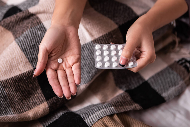 Vrouw houden blisterverpakking witte medische pillen tabletten pijn maag menstruatie periodes cyclus hoofdpijn slapeloosheid. Dame ziek koude koorts bevriezen, migraine concept symptomen. Noodoproep - Foto, afbeelding