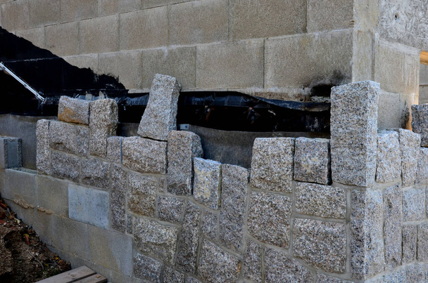 стек и клей натуральных камней к бетонной стене здания. Разложить блоки по земле, чтобы соединиться друг с другом. каменщик работает каждый стык - Фото, изображение