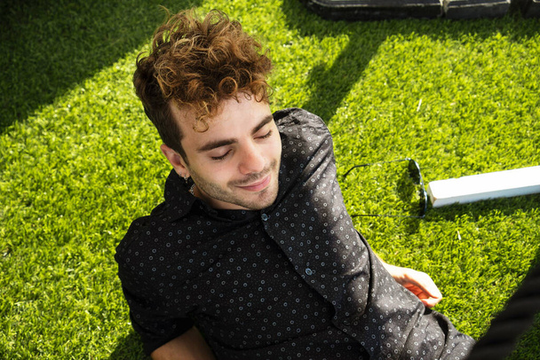 A young attractive man lying on artificial grass and relaxing - Фото, зображення