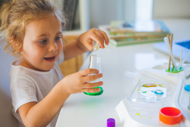 Wetenschap. Klein schattig meisje zet experimenten thuis, gekleurde vloeistoffen, laboratorium kind installatie. School. - Foto, afbeelding