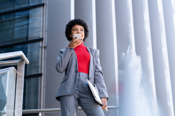 A young African-American businesswoman talking on the phone in a business building - Valokuva, kuva