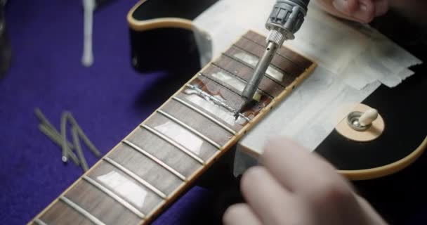 Luthier lämmittää tuskailla kitara juottamalla rautaa ennen refretting, kitara käsityöläiset valmistelut frets korvaaminen sähkökitara, 4k 60fps Prores HQ - Materiaali, video