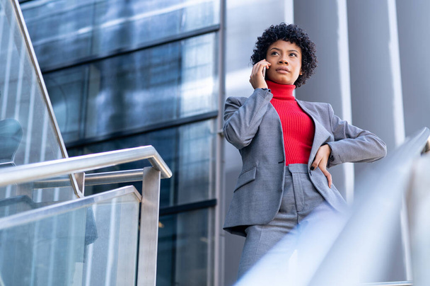 A young African-American businesswoman talking on the phone in a business building - Foto, imagen