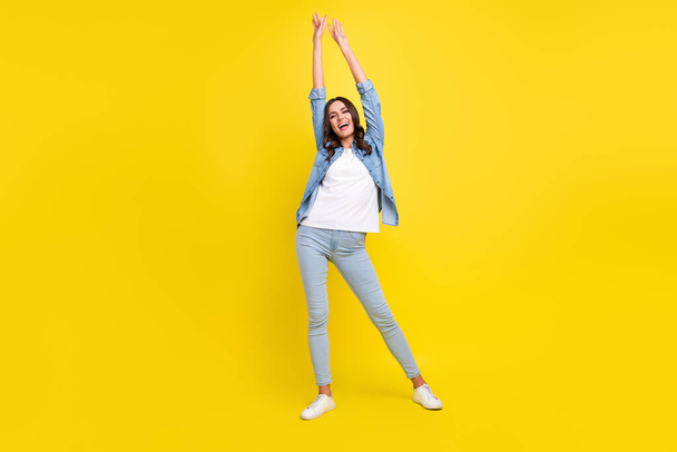 Photo of funny adorable young lady wear jeans shirt smiling dancing isolated yellow color background - 写真・画像