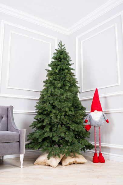 Árbol de Navidad primer plano sin juguetes. Gnomo elfo de juguete rojo cerca del árbol de Navidad. Buen espíritu de Año Nuevo. - Foto, imagen