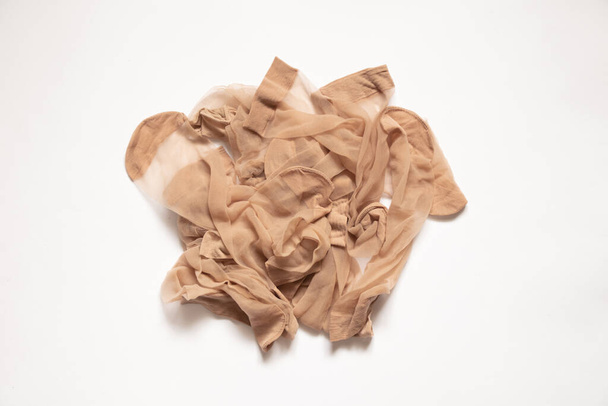 a pile of old dirty nylon brown socks on a white background, nylon sock, a lot of women's socks - 写真・画像
